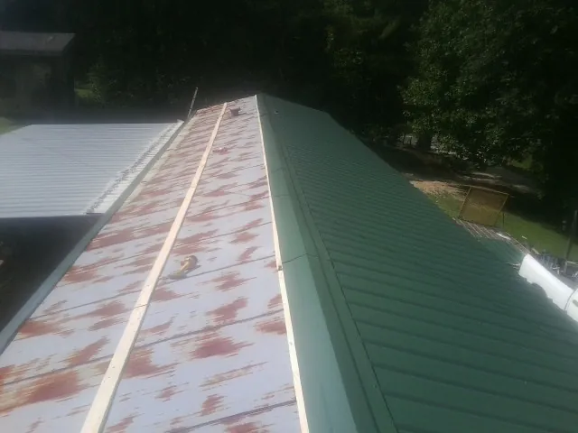 Old rusted panels beside newly installed green metal roofing — Wind Damage Roof Repair by Roofing Brothers in Waxhaw