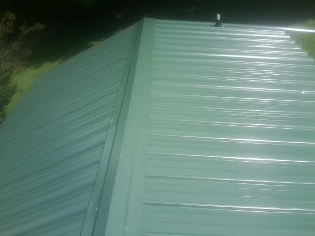 New green metal panels meeting at the ridge of a roof — Flat Roof Repair work by our crew in Waxhaw