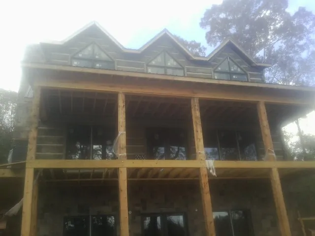 Dormers and porch framing on a large log home under construction — Roof Coating work by our crew in Waxhaw