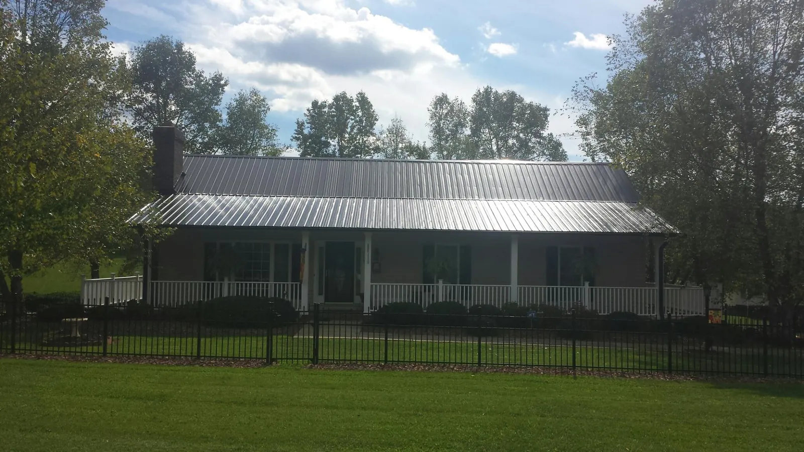 Gray metal roof on a brick ranch with a full width front porch — Gutter Guard Installation work by our crew in Waxhaw