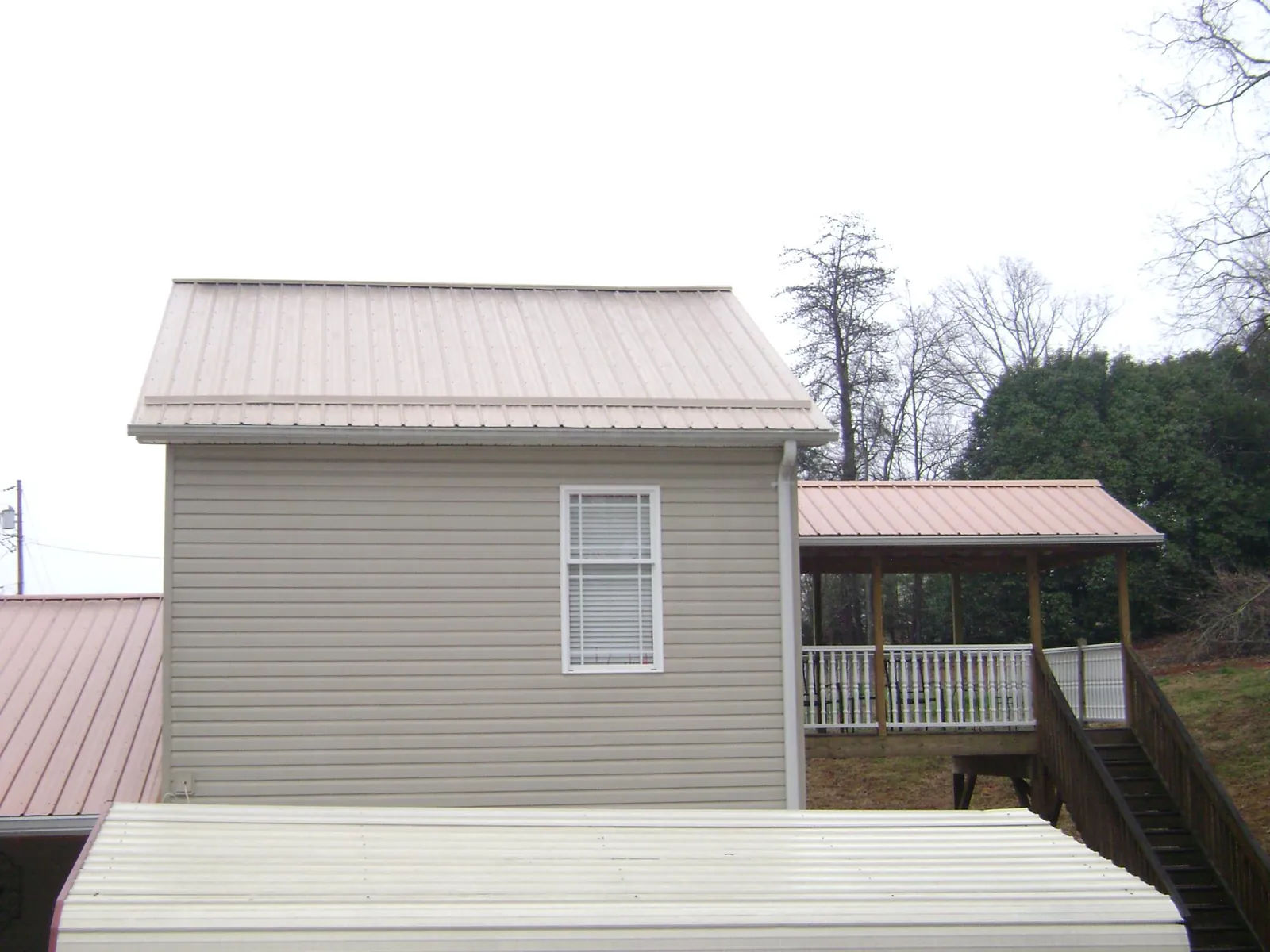 Tan metal roofs on a two story addition and attached porch, from a Roof Replacement job in Waxhaw