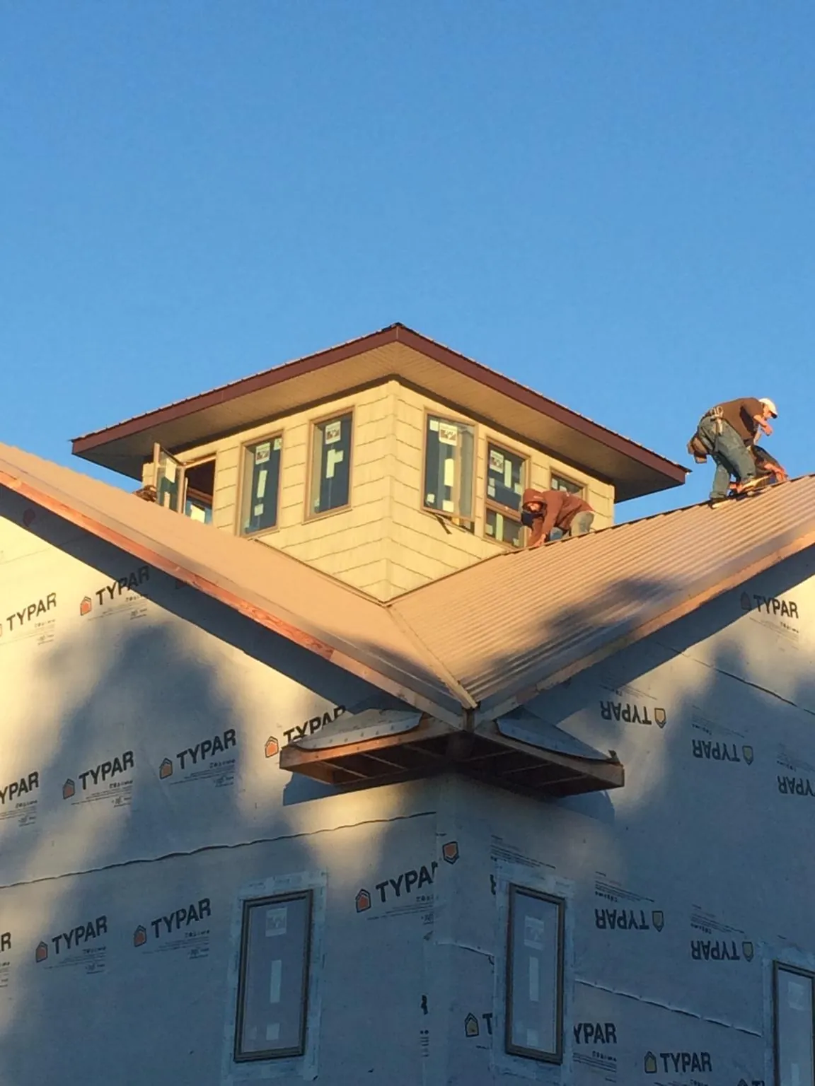 Roofers working around a rooftop cupola on a new metal roof at sunset — Roof Waterproofing in Waxhaw by Roofing Brothers